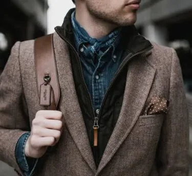 Man in layered casual blazer outfit with leather strap bag