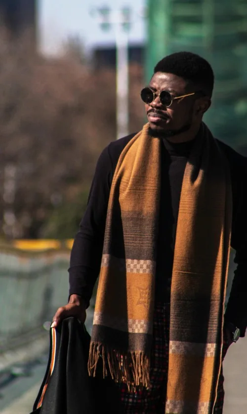 Stylish man in sunglasses wearing a dark sweater and patterned scarf – smart casual spring outfit