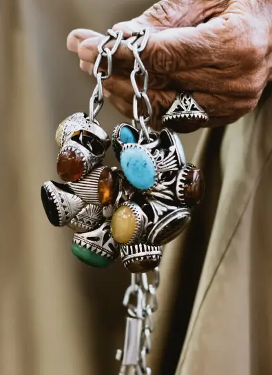 Mens accessories - gem rings A hand holding a chain adorned with ornate gemstone rings, showcasing unique men's accessories.
