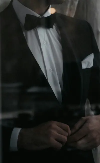 A man adjusting his tuxedo and bow tie, representing smart casual wear for men.