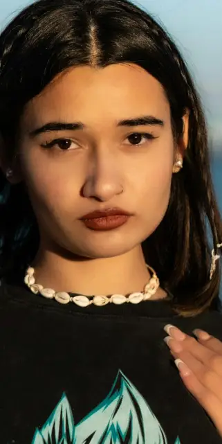 90s accessories - puka shell necklace Woman wearing a shell necklace with a confident expression at sunset.