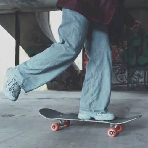 Men's 90s Clothing - baggy A person wearing baggy jeans and sneakers skateboards in a grungy setting, reflecting men's 90s clothing style.
