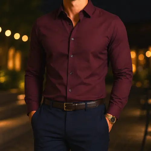 Man wearing a well-fitted burgundy long sleeve button-up shirt with blue pants at night
