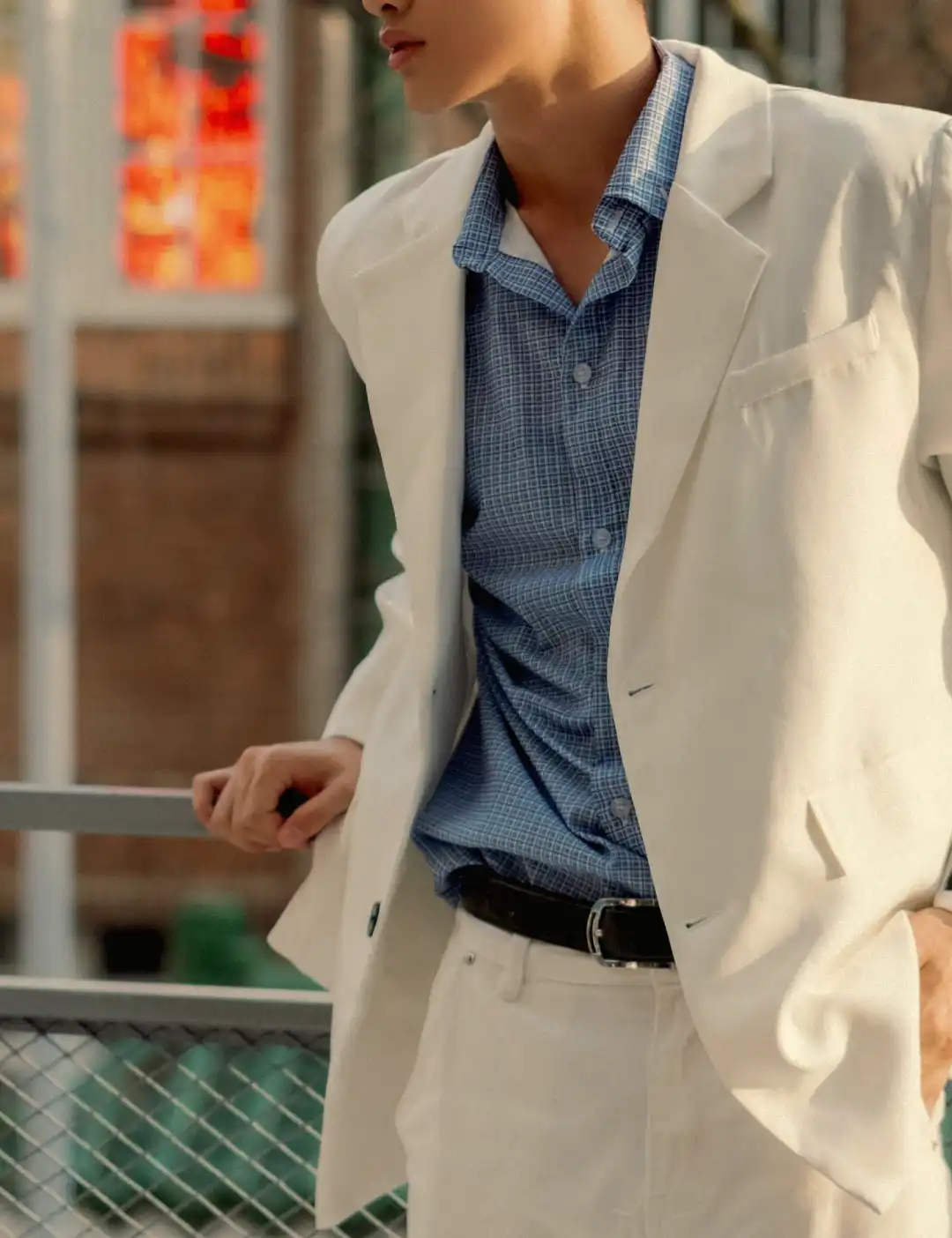 Man wearing a light cream summer suit with a blue shirt in a casual warm-weather setting.