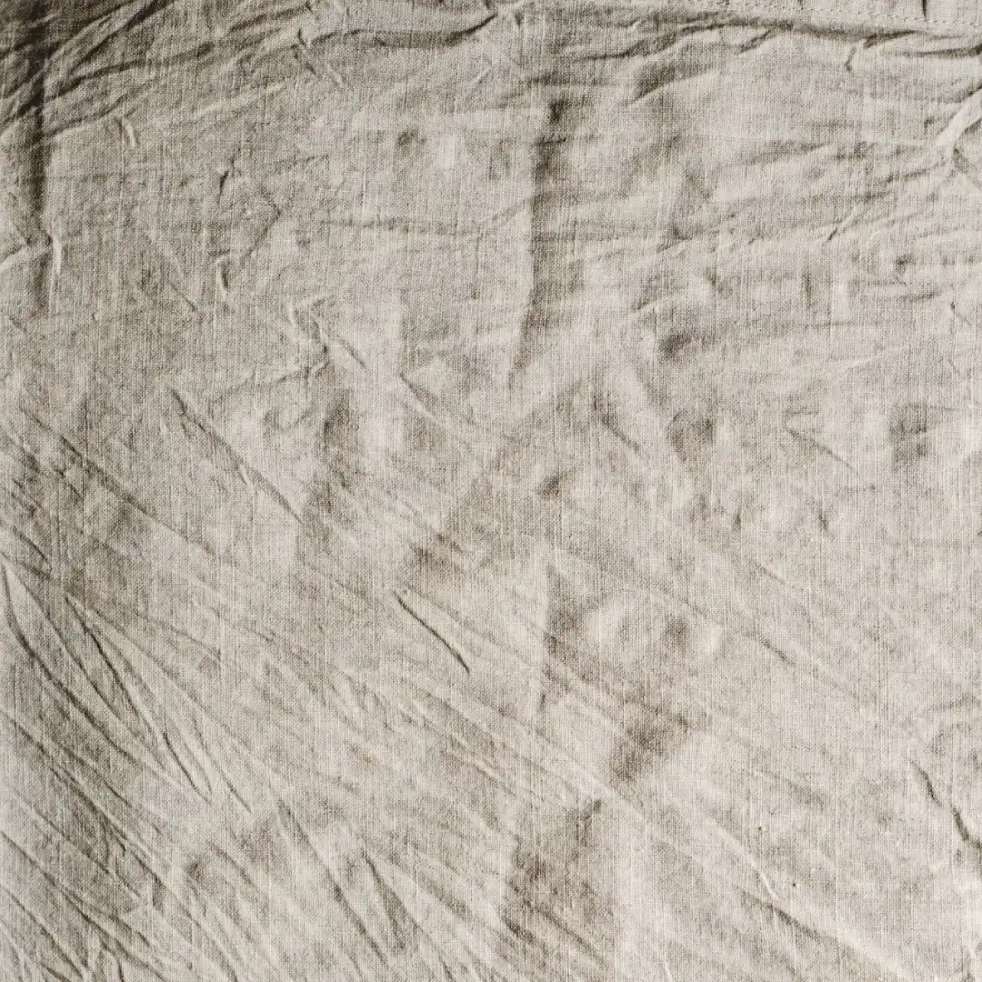 Close-up of wrinkled linen fabric, a lightweight material commonly used in summer suits for men.