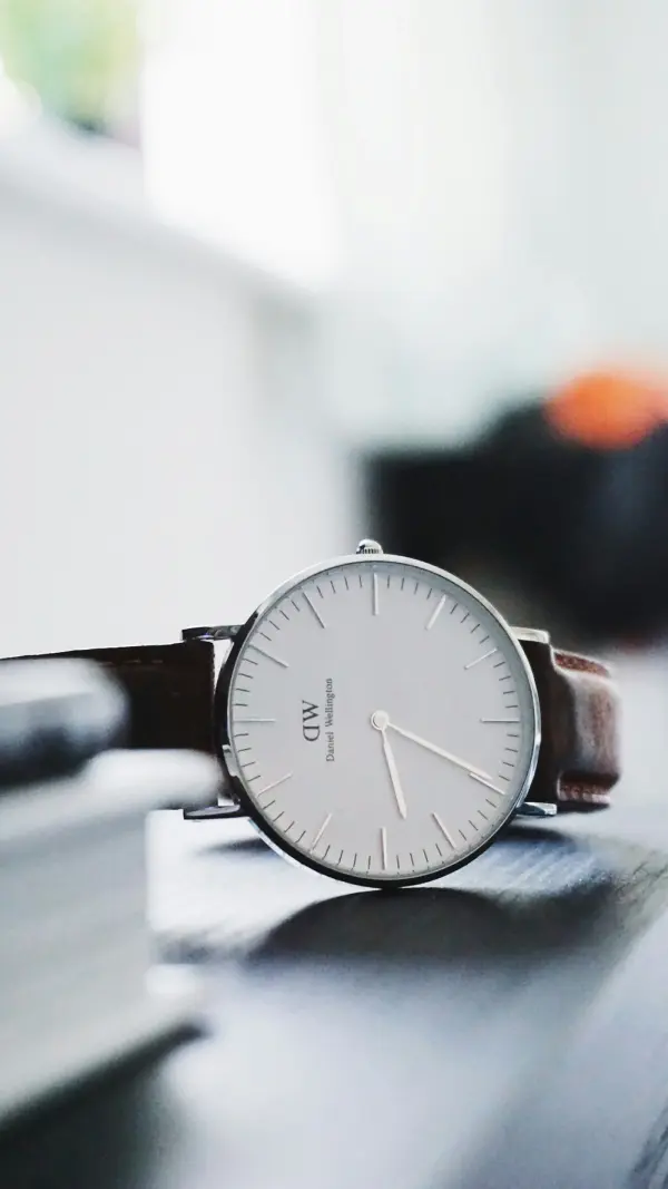 Minimal silver watch with a brown leather strap styled as a Dark Academia Accessory.