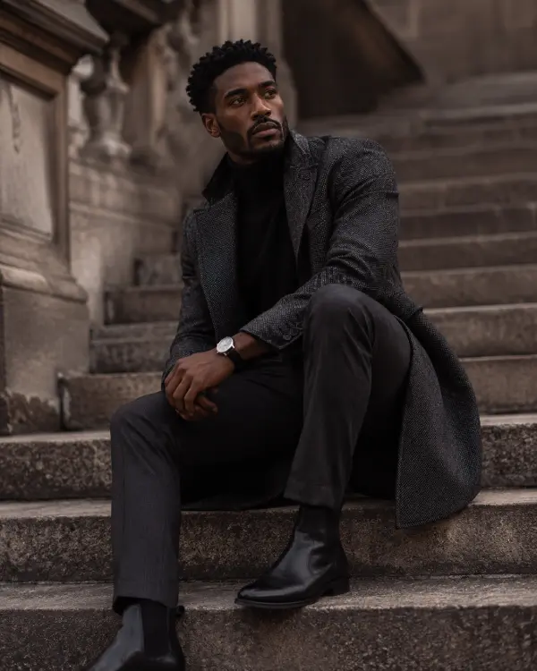 Man wearing a charcoal overcoat, black turtleneck, Chelsea boots, and watch with Dark Academia Accessories.