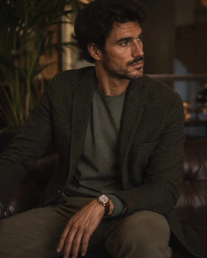 Man showing how to wear monochrome with an olive green shirt, matching trousers, and a dark textured blazer.