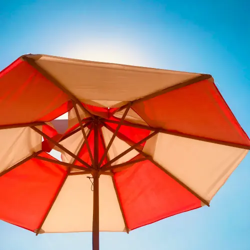 Bright red and white sun umbrella representing sunscreen protection in a skincare routine for men.
