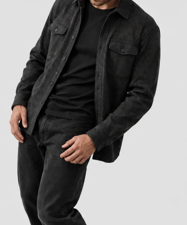 Man wearing an all black outfit with a textured overshirt, black T-shirt, and faded black jeans.